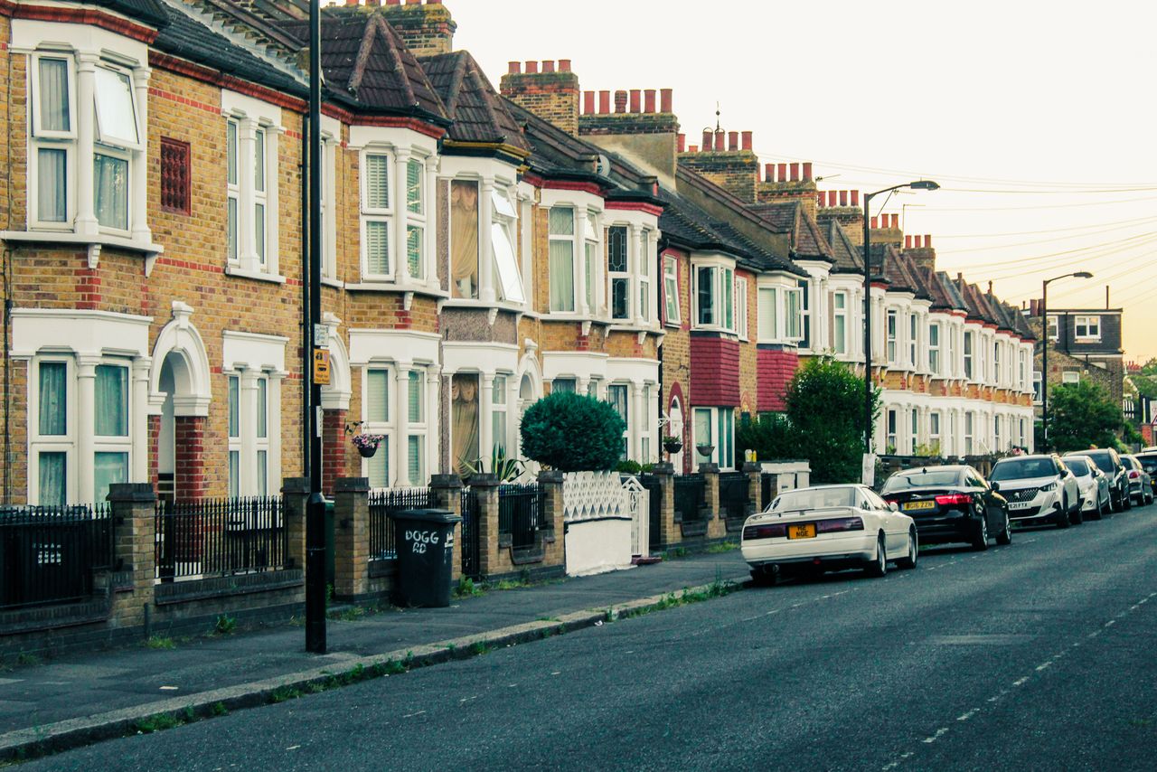 Charming view of traditional London terraced houses and parked cars along a quiet street at dusk.
