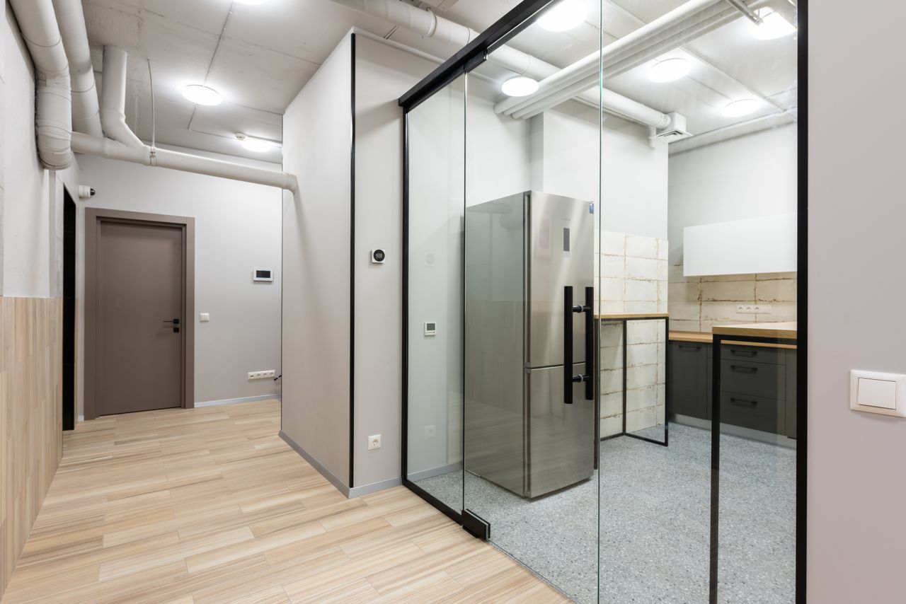 Interior of spacious hallway and kitchen with counters and appliances in contemporary workplace